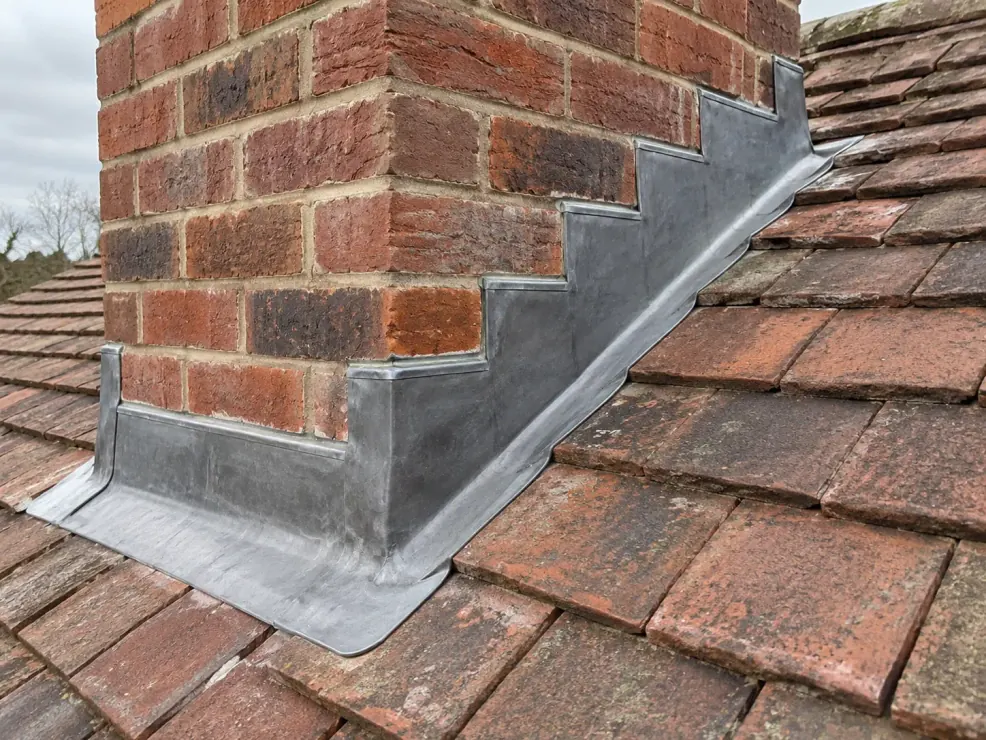 New stepped lead flashing fitted around a brick chimney