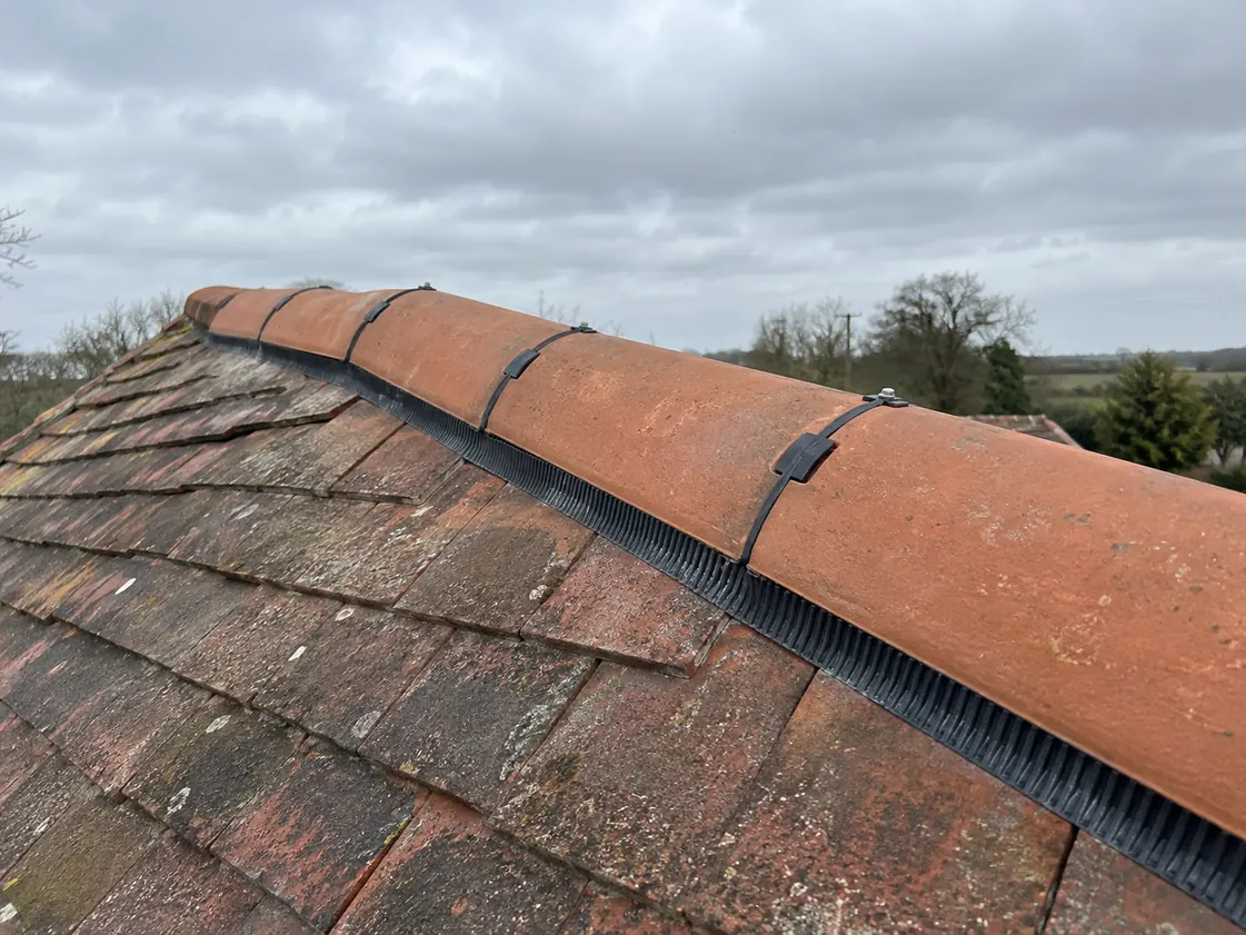 Ridge tiles being repaired along the top of a pitched roof